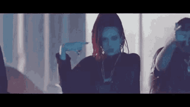a woman with red hair and dreadlocks is dancing in a dark room with a group of people .