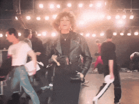 a woman in a leather jacket stands in a crowd of people