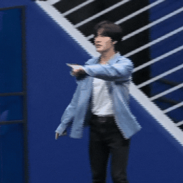 a man in a blue shirt is standing on a staircase with his arms in the air