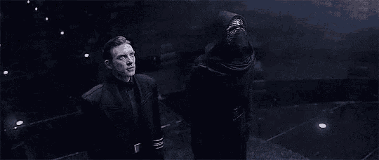 a man is standing next to a man in a black hooded costume .