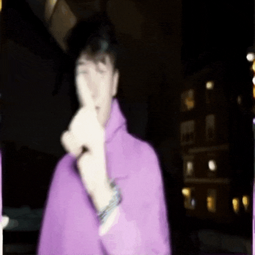 a man in a purple hoodie is giving a middle finger .