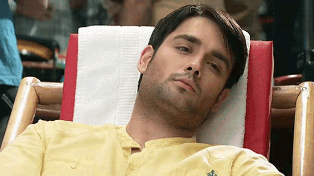 a man in a yellow shirt is laying on a red and white striped chair