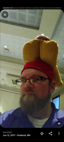 a man with a beard wearing a red hat with a chicken on it