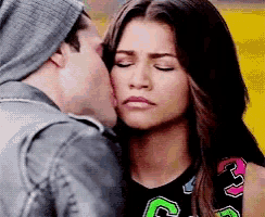 a man is kissing a woman on the cheek and she is wearing a shirt with the letter c on it