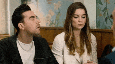 a man and a woman are sitting at a table talking to each other .