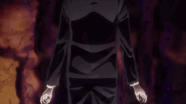 a man in a black suit is standing in the dark with his hands outstretched .