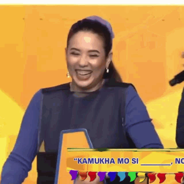 a woman is smiling behind a sign that says kamukha mo si