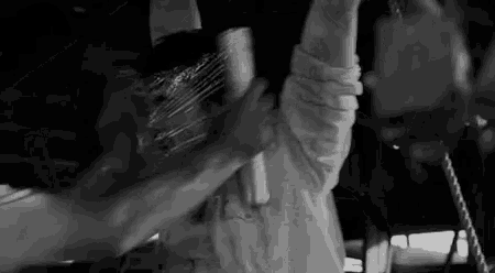 a black and white photo of a man holding a microphone in a room .