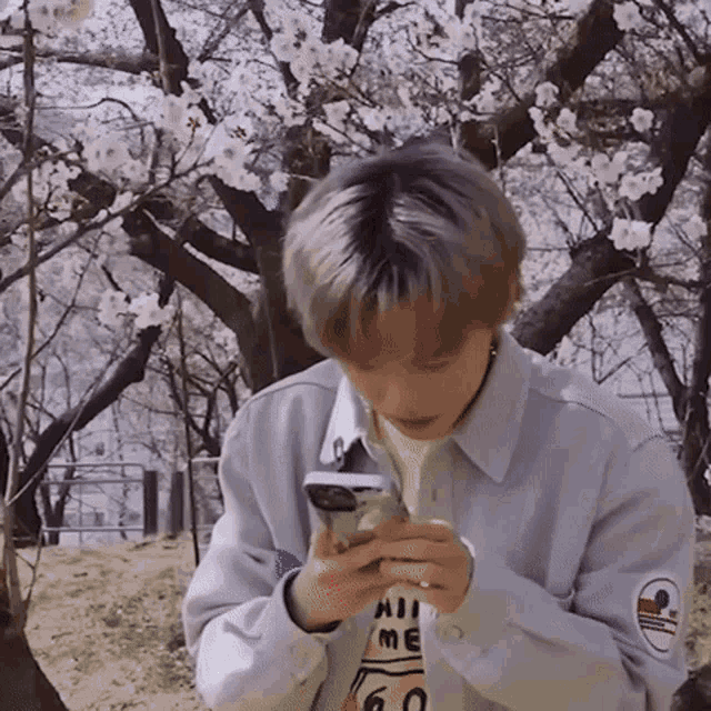 a man wearing a shirt that says " hi me " is looking at his phone