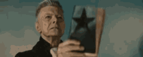a man in a black suit is holding a book with a black star on it .