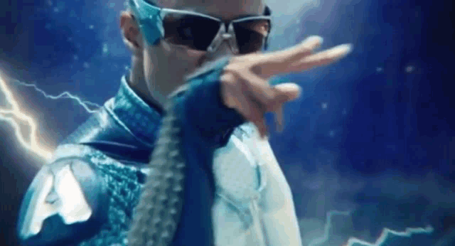 a man in a blue superhero costume is making a peace sign with his hand .