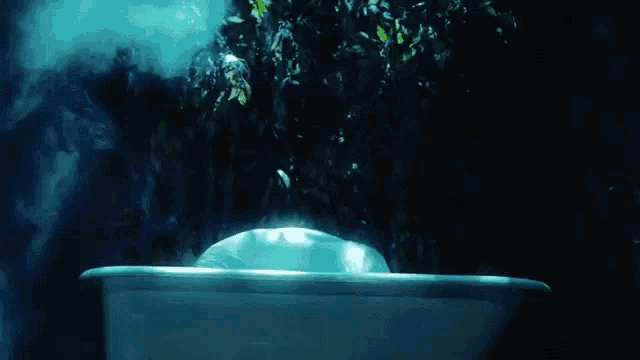 a man in a white shirt is standing in a bathtub surrounded by blue smoke .