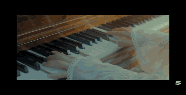 a woman in a white dress is playing a piano in a video