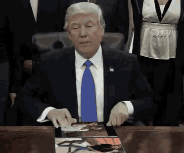 a man in a suit and tie is sitting at a table with a magazine on it
