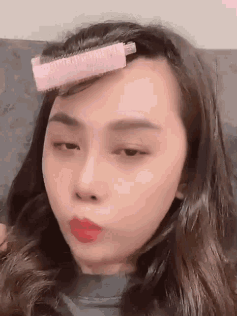 a woman with a pink roller in her hair making a funny face