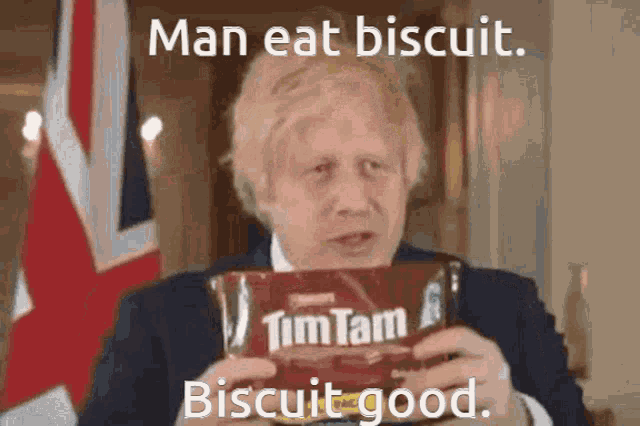 a man is holding a bag of tim tam biscuits and says man eat biscuit biscuit good