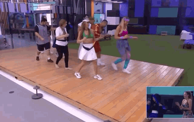 a group of people are dancing on a stage in a gym