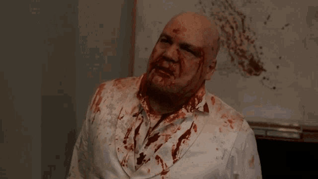 a man with blood on his shirt has the word come on above his head