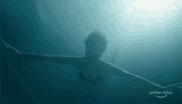 a woman is swimming in the ocean with a prime video logo in the background