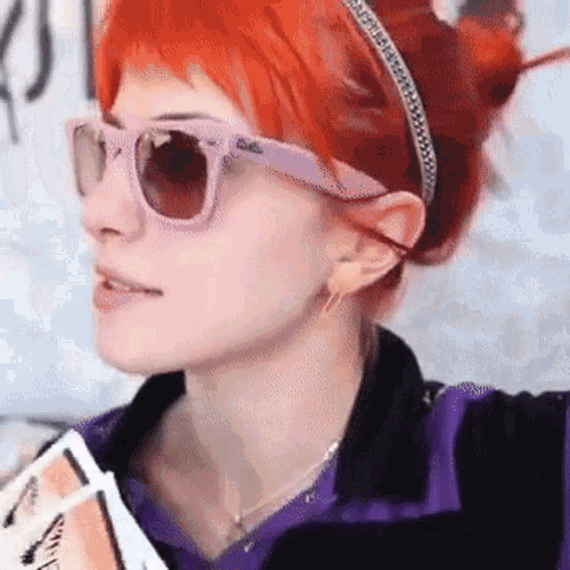 a woman with red hair is wearing pink sunglasses