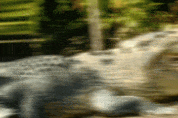a blurry picture of a waterfall in the woods with trees in the background