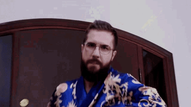 a man with a beard is wearing a blue robe and glasses