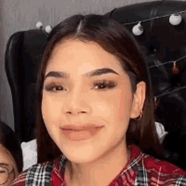a close up of a woman 's face with a plaid shirt on .