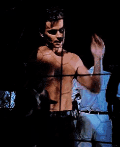a man without a shirt is standing in front of a mirror .