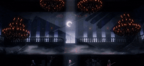 a group of people are playing instruments in a dark room with chandeliers