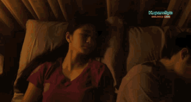 a woman laying next to a man in a bed with the words kapamilya online live on the bottom right