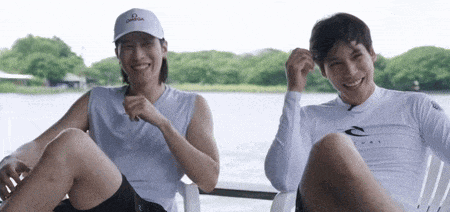two young men are sitting next to each other on a boat in the water .