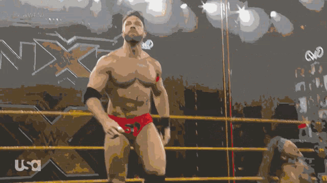 a man in a wrestling ring with the word nxt on the wall