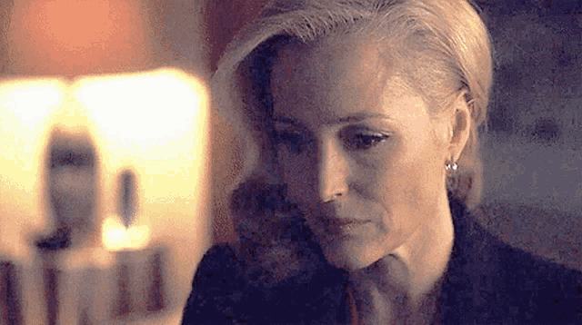 a close up of a woman 's face in a dark room with a candle in the background .