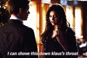 a man and woman are standing next to each other and the woman says i can shove this down klaus 's throat .