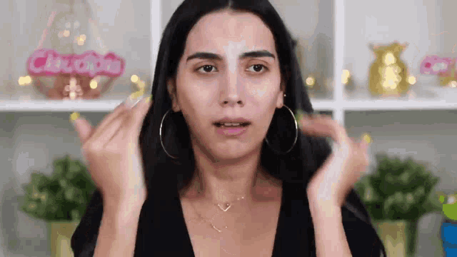 a woman without makeup is making a funny face with her hands .