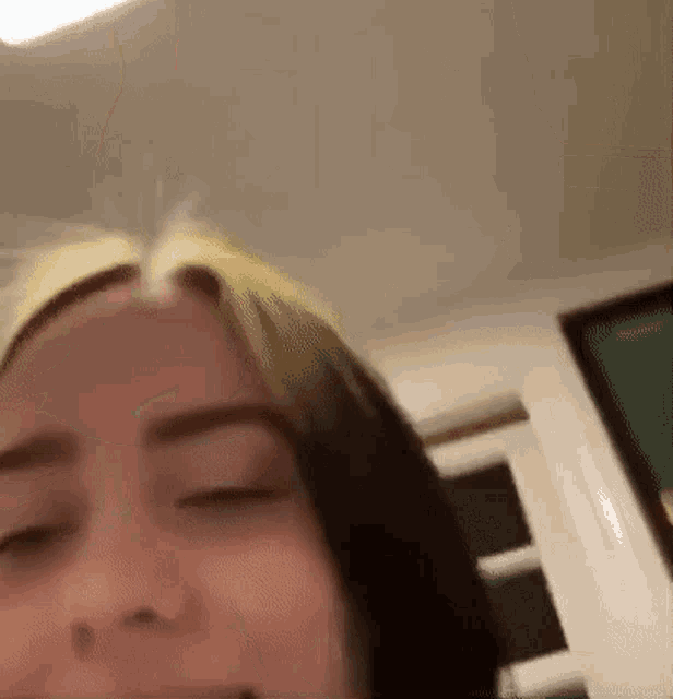 a close up of a woman 's face with her eyes closed and her hair in a ponytail .