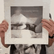 a person is holding a piece of paper in front of their face with a picture of a dog on it .