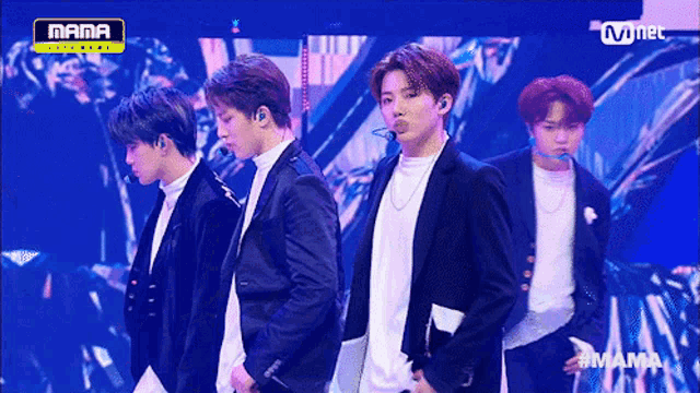 a group of young men are standing on a stage with a sign that says mama on it