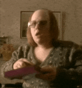 a woman wearing glasses and a sweater is holding a purple object in her hands .