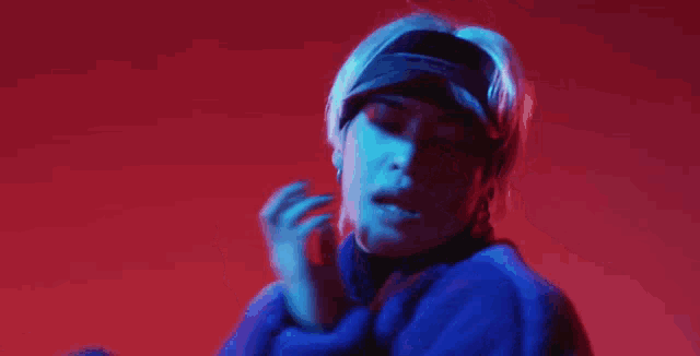 a person wearing a hat and a blue jacket is standing in front of a red wall