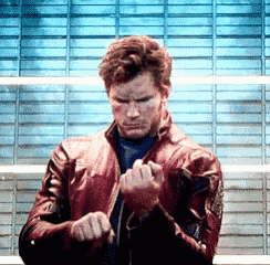 a man wearing a red leather jacket is standing in front of a blue wall .