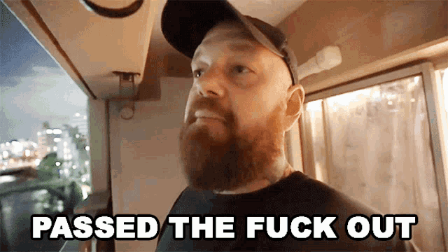 a man with a beard says passed the fuck out in front of a window