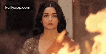 a woman is standing in front of a fire in a room .