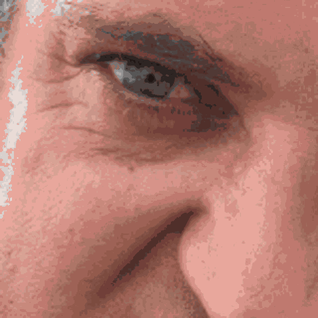 a close up of a man 's face with a blue eye and a red nose .