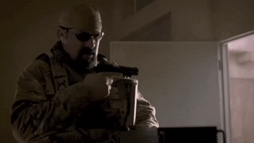 a man in a military uniform is holding a gun in his hand .