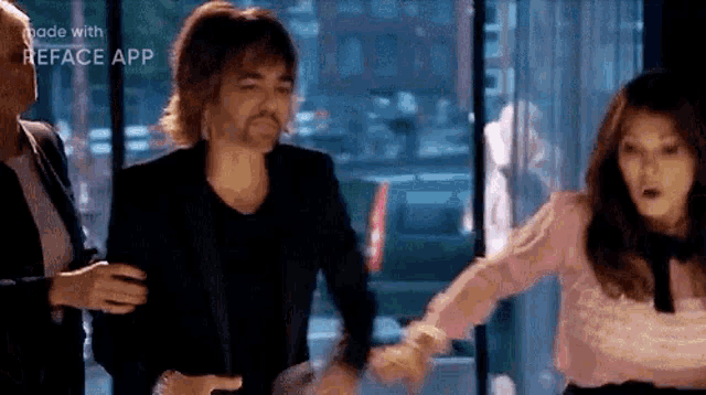 a man with a fake mustache is being held by two women .