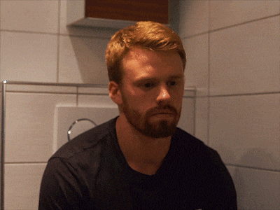 a man with red hair and a beard is sitting on a toilet