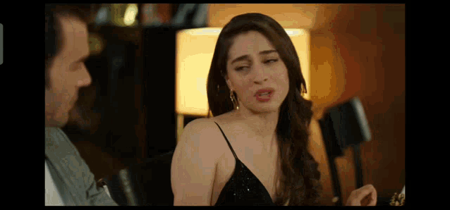 a woman in a black dress is talking to a man in a suit .