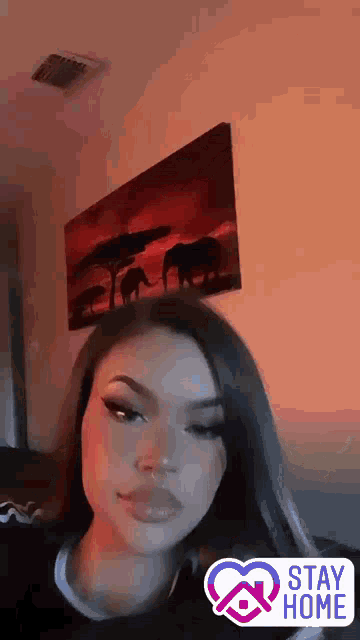 a woman is sitting on a couch in front of a painting on the wall .