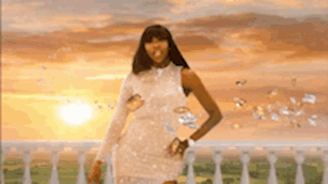 a woman in a white dress is standing on a balcony overlooking a field .